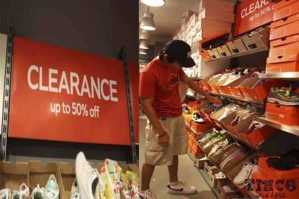 A man browsing shoes at a clearance sale in a store.