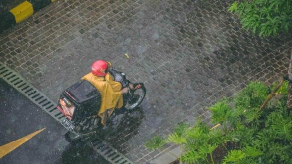 An aerial view of a man riding a motorcycle in the rain, captured in Metro Manila.