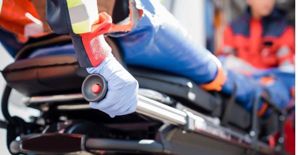Paramedic in uniform pushing a stretcher with a patient in an ambulance.