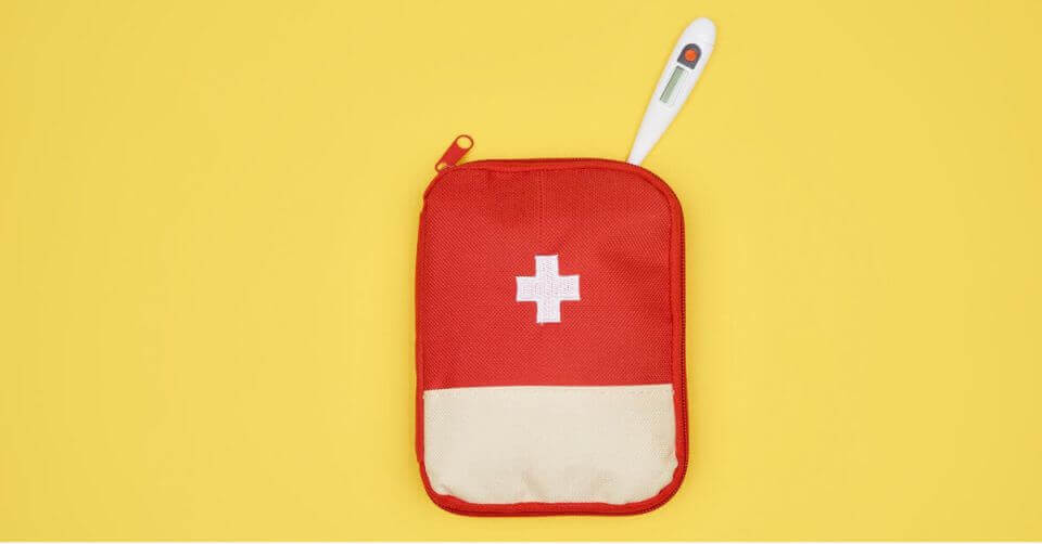 Red first aid kit with a white cross and a thermometer on a yellow background.