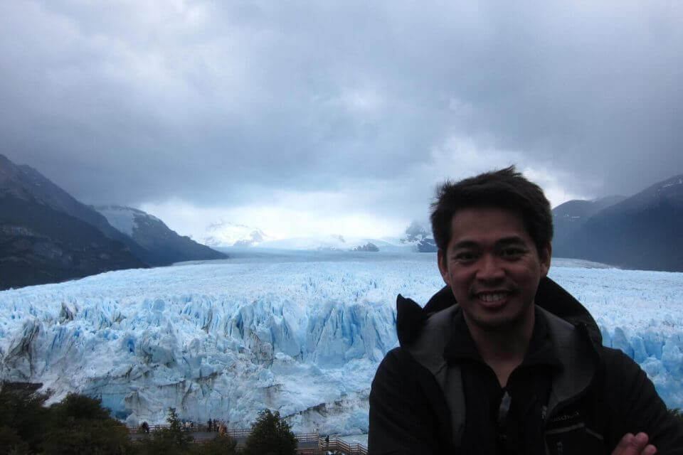 A man marveling at a glacier in GALÀ, a travel book celebrating wanderlust.