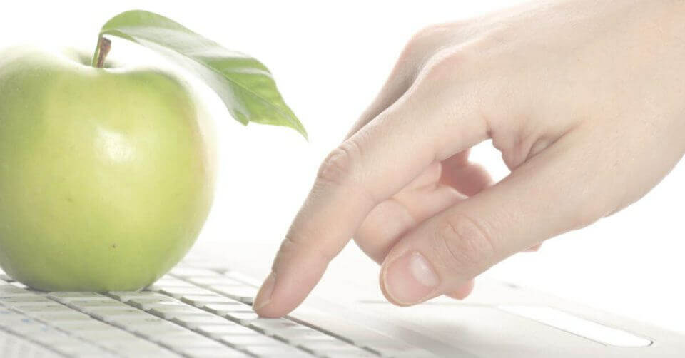 A hand demonstrates how to take a screenshot on a Mac using a green apple and laptop.
