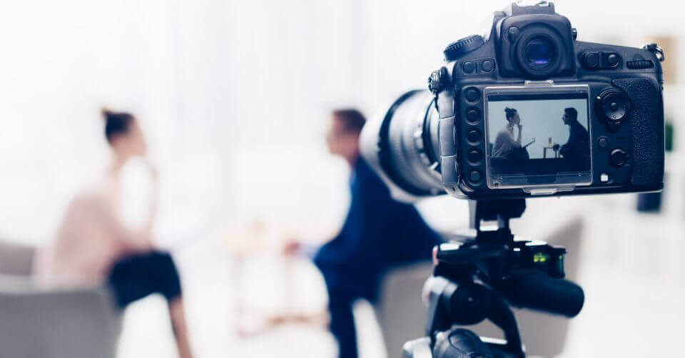 A video camera is being used to take a picture of a group of people while following practical tips for recording oneself.