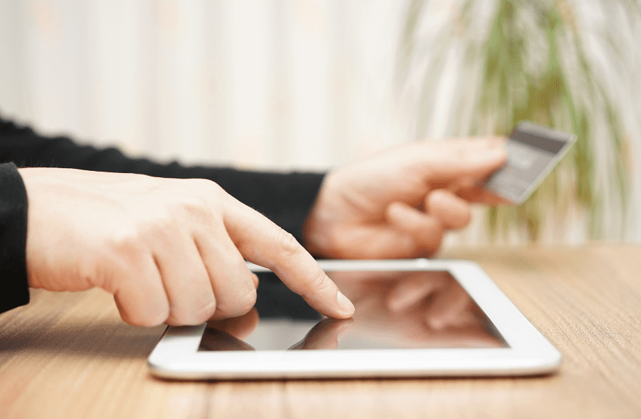 A person holding a credit card and using a tablet computer to access complete Philippine bank Swift codes.