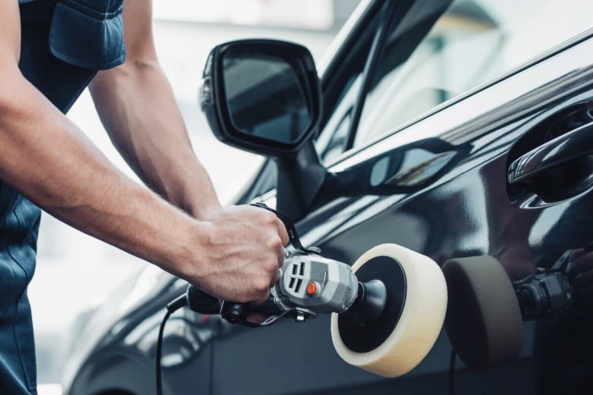 A man is polishing the door of a black car in Metro Manila.