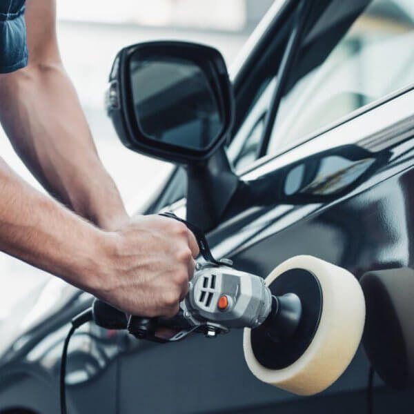 A man is polishing the door of a black car in Metro Manila.