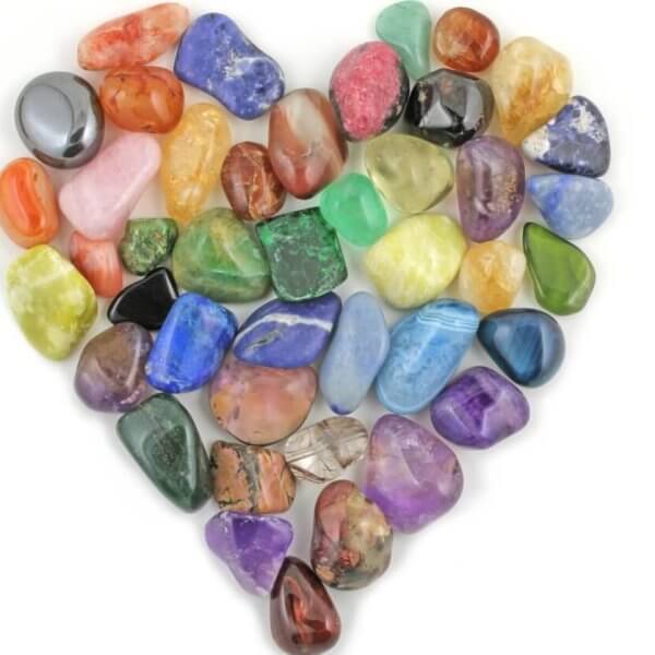 A heart shaped arrangement of colored crystals on a white background.