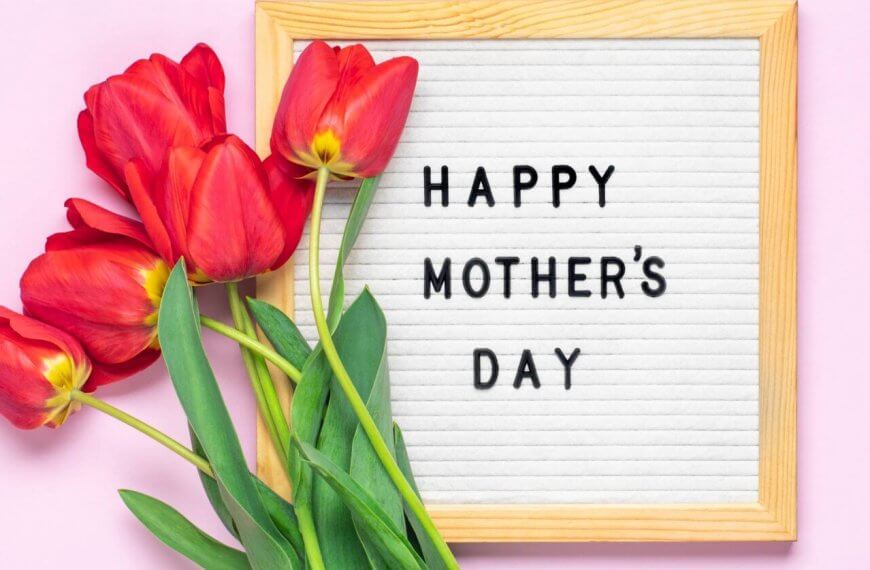 A Mother's Day celebration greeting with red tulips alongside a framed white letter board that reads "happy mother's day" on a pink background.