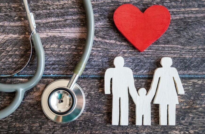 A stethoscope is positioned on the left side of the image, with its ear tubes and chest piece visible. A red wooden heart lies to the right of the stethoscope. Next to the heart, there's a white wooden cutout depicting a family of three holding hands. This scene evokes Hi-Precision Diagnostics centers in Metro Manila.
