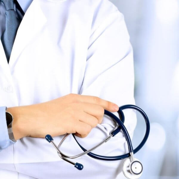 Close-up of an otolaryngologist wearing a white coat with a stethoscope draped around their neck. The doctor has their arms crossed, gripping the stethoscope. The background is blurred, featuring a bright, clinical setting in Metro Manila.