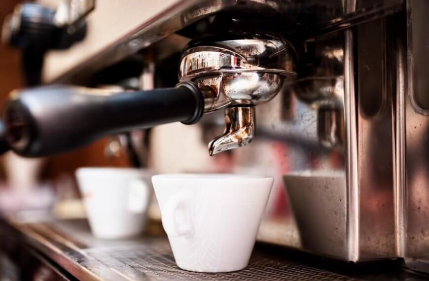 Close-up of a professional espresso machine in action, with a portafilter and spout dispensing coffee into a white ceramic cup below. The shiny metal surface of the machine reflects the bustling environment, hinting at Davao's best coffee place—a must-try for any café enthusiast.