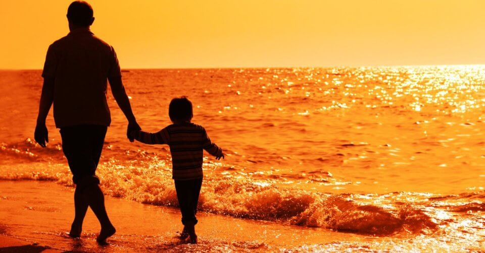A silhouette of an adult and child holding hands while walking along a beach at sunset captures the essence of heartfelt messages. The sky and ocean are drenched in warm orange and golden hues, with gentle waves lapping at the shore, creating a serene scene that conveys tranquility and togetherness.