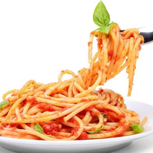 A fork twirls spaghetti topped with tomato sauce, garnished with a fresh basil leaf, lifted above a white plate filled with more spaghetti. The background is plain white, emphasizing the colorful dish—just like you'd experience at the best restaurants in One Ayala dining.