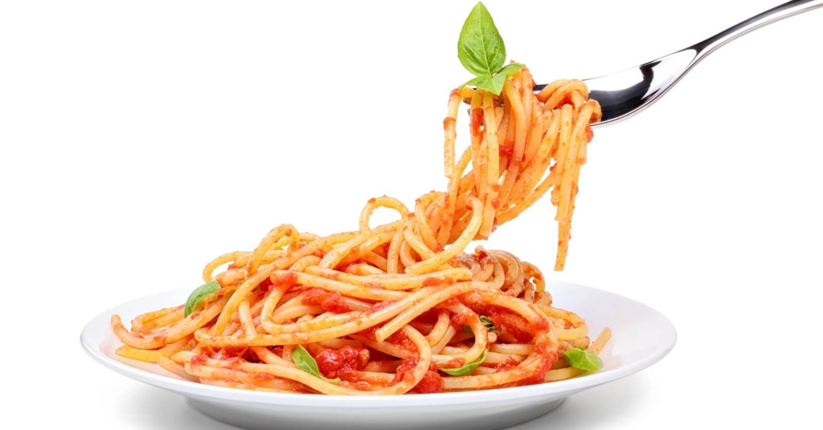 A fork twirls spaghetti topped with tomato sauce, garnished with a fresh basil leaf, lifted above a white plate filled with more spaghetti. The background is plain white, emphasizing the colorful dish—just like you'd experience at the best restaurants in One Ayala dining.