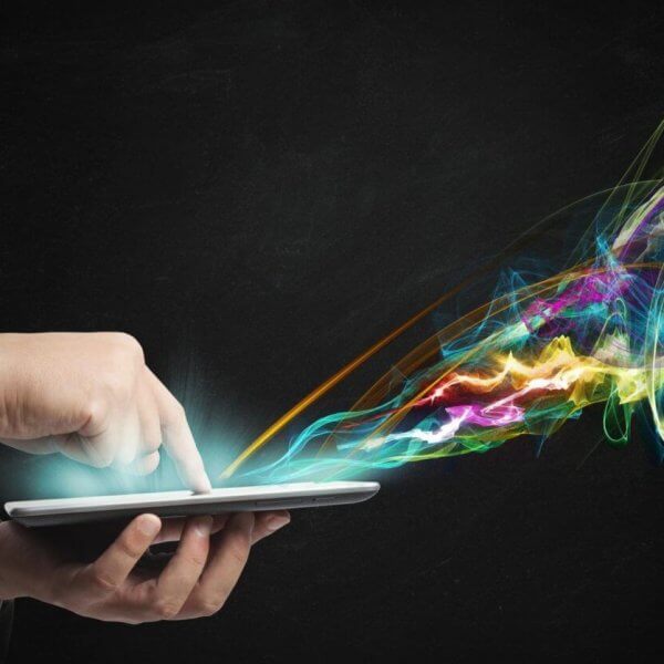 A person in a suit uses a tablet, with colorful, swirling light trails emanating from the screen against a dark background. This vibrant display of blues, greens, yellows, pinks, and purples resembles the dynamic pulse of IT companies in Metro Manila.