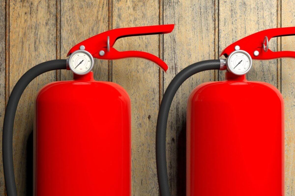 Two bright red fire extinguishers with black hoses and pressure gauges are mounted against a rustic wooden wall in Manila. The sleek, vibrant red of the extinguishers contrasts with the natural wood texture, while suppliers ensure timely fire extinguisher refills to maintain safety standards.