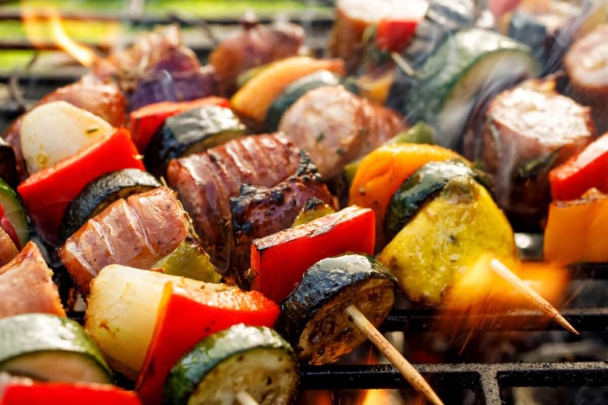 Grilled skewers with zucchini, bell peppers, onions, and meat sizzle over open flames, reminiscent of a vibrant evening in Iligan City.