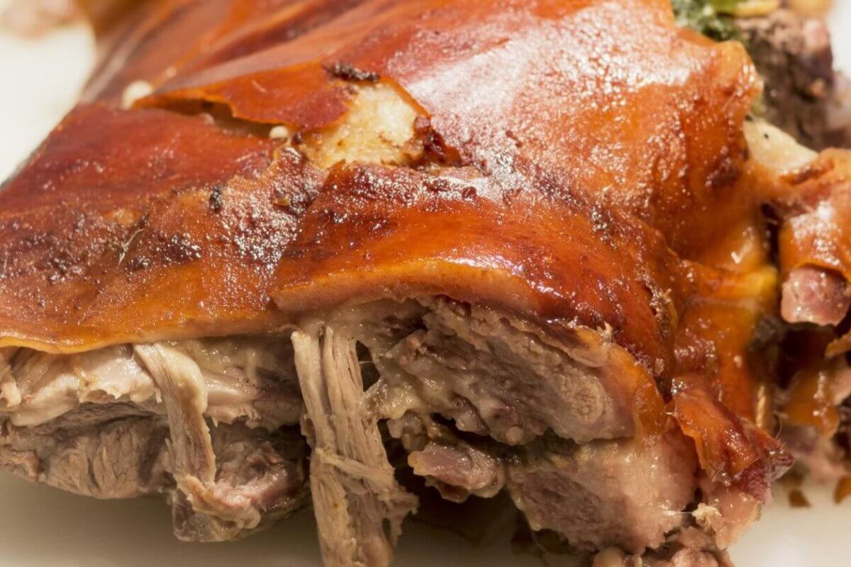 Close-up of crispy roast pork with golden skin and tender meat on a white plate, reminiscent of the flavors celebrated in Meycauayan's renowned restaurants.