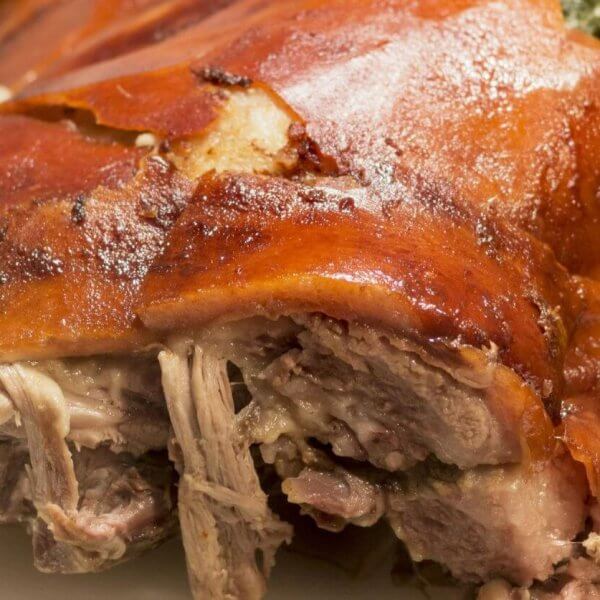 Close-up of crispy roast pork with golden skin and tender meat on a white plate, reminiscent of the flavors celebrated in Meycauayan's renowned restaurants.