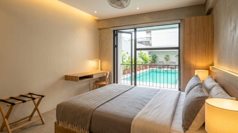 Bright budget hotel room in Metro Manila with a glimpse of an outdoor pool, representing an under-₱3,000 staycation stay