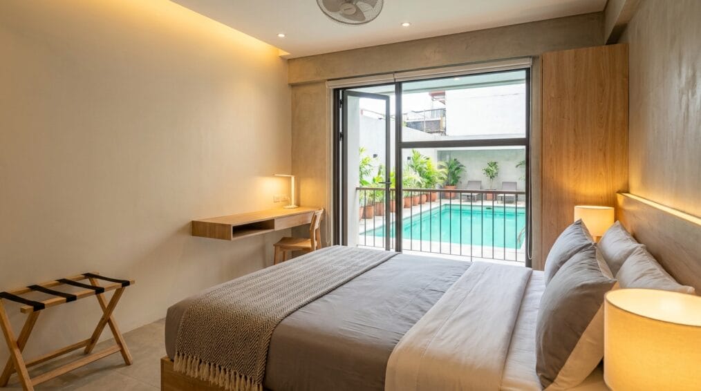 Bright budget hotel room in Metro Manila with a glimpse of an outdoor pool, representing an under-₱3,000 staycation stay