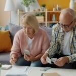 Is a Pre-Need Plan Worth It in the Philippines? (2026 Guide) Senior Filipino-style couple reviewing pre-need plan and financial paperwork together at home, deciding whether a memorial or education plan is worth signing