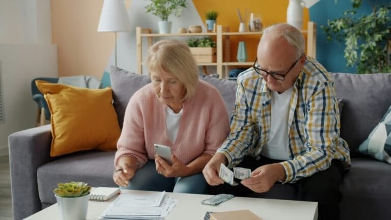 Senior Filipino-style couple reviewing pre-need plan and financial paperwork together at home, deciding whether a memorial or education plan is worth signing