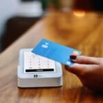 Filipino shopper holding a credit card in front of a payment terminal at a store checkout, about to choose between paying cash or taking a 0% installment plan