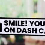 Rounded corner dash cam warning sticker applied to a car window, indicating the vehicle records footage while driving