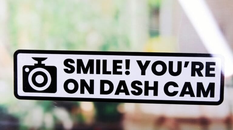 Rounded corner dash cam warning sticker applied to a car window, indicating the vehicle records footage while driving