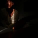 Person alone at night watching a streaming video on a smartphone in bed, illustrating the decision of whether a Vivamax (VMX) subscription in the Philippines is worth paying for