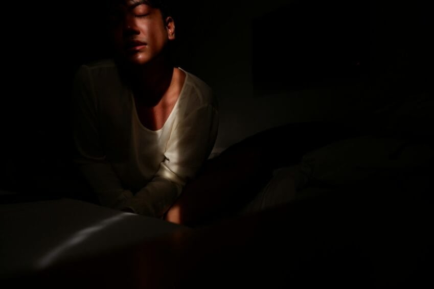 Person alone at night watching a streaming video on a smartphone in bed, illustrating the decision of whether a Vivamax (VMX) subscription in the Philippines is worth paying for
