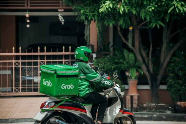 Grab delivery rider on a motorcycle with the green Grab delivery bag, representing the GrabFood and GrabCar discounts included in a GrabUnlimited subscription in the Philippines