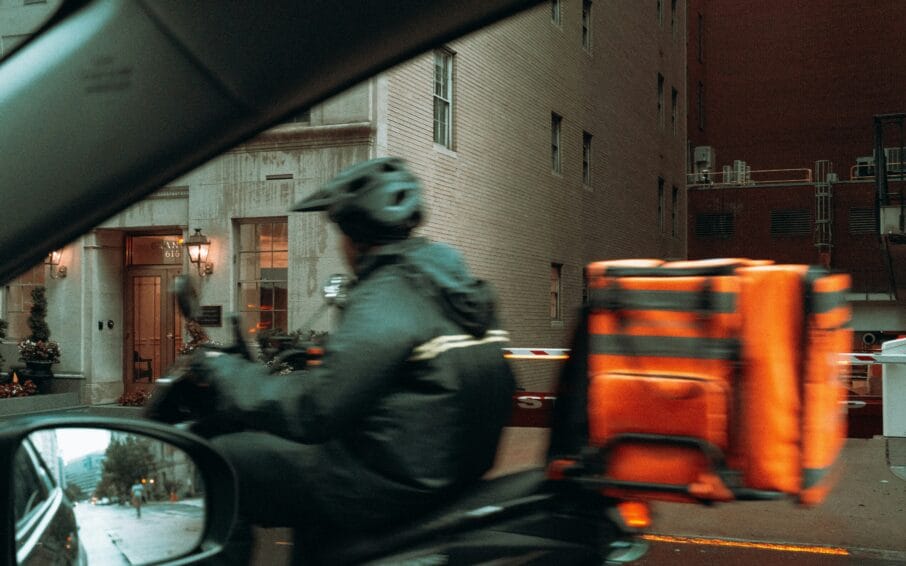 Delivery rider on a scooter carrying an insulated delivery bag, the kind of setup GrabMart and foodpanda Pandamart riders use for grocery delivery in the Philippines