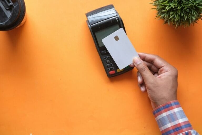 Person holding a credit card near a payment terminal in the Philippines, illustrating whether a rewards or cashback credit card's annual fee is worth paying