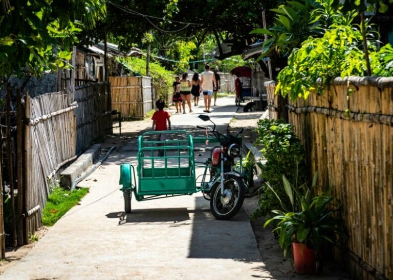 Motorcycle and tricycle parked on a residential Philippine street — the everyday ride behind the CTPL-vs-comprehensive insurance decision