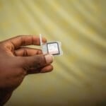 Close-up of a hand holding a smartphone with its SIM card tray open, illustrating the SIM/device swap involved in choosing a postpaid mobile plan in the Philippines