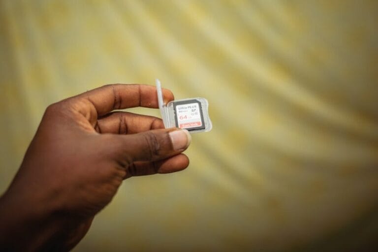 Close-up of a hand holding a smartphone with its SIM card tray open, illustrating the SIM/device swap involved in choosing a postpaid mobile plan in the Philippines