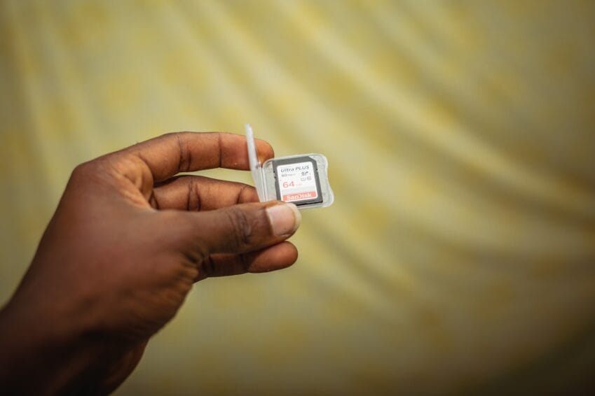 Close-up of a hand holding a smartphone with its SIM card tray open, illustrating the SIM/device swap involved in choosing a postpaid mobile plan in the Philippines