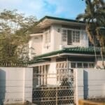 Two-story Philippine subdivision house with white facade and green tile roof, the kind of property a renting-vs-buying decision in the Philippines usually comes down to