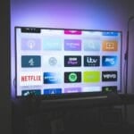 TV screen showing a grid of streaming service app icons in a dim living room, representing the multiple paid subscriptions like Netflix, Disney+, and Max that Filipino households juggle