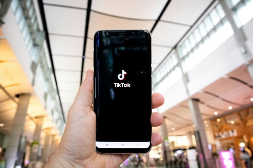 Shopper opening the TikTok app on a phone inside a mall, illustrating how to verify a seller before buying from TikTok Shop, Shopee, or Lazada live selling in the Philippines