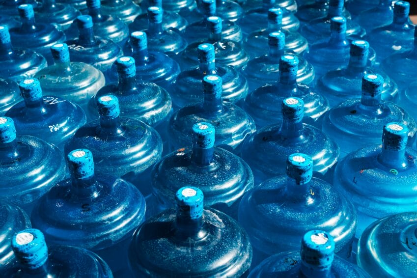 Rows of blue 5-gallon water containers, the kind refilled at Philippine water refilling stations or delivered by brands like Summit and Absolute