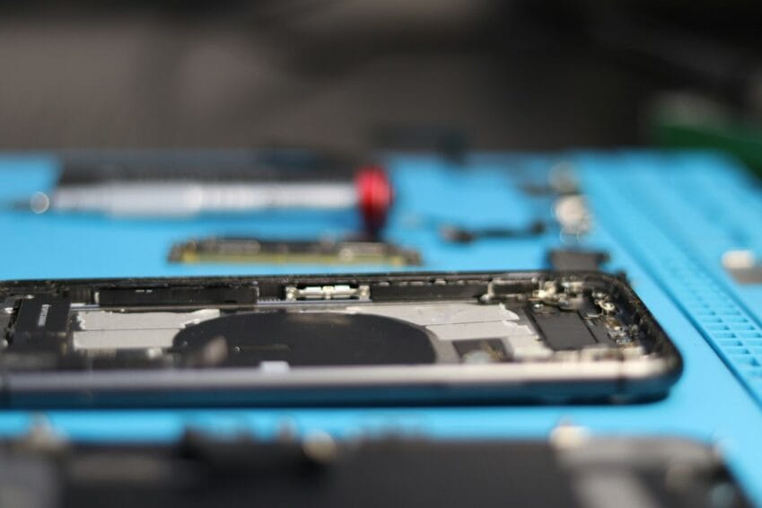 Technician disassembling an iPhone to replace parts, the kind of repair work an Apple Authorized Service Provider in the Philippines must document and warranty