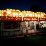 A brightly lit branded food cart stand selling fries at night, the kind of small food cart franchise setup covered in this guide