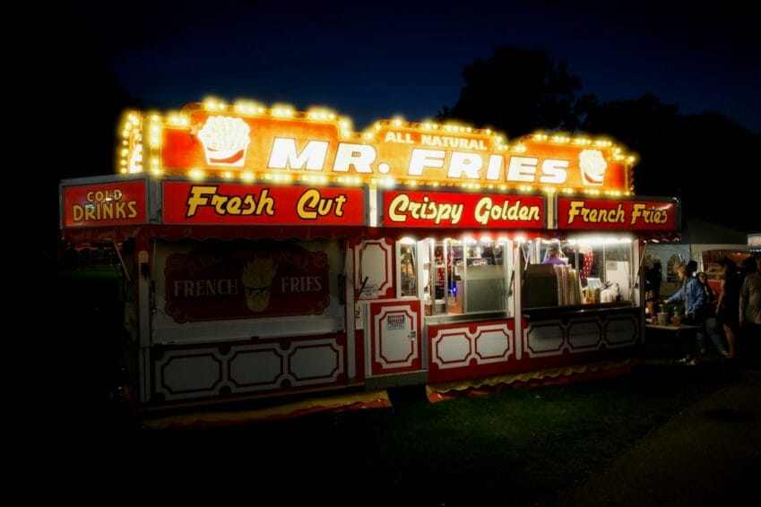 A brightly lit branded food cart stand selling fries at night, the kind of small food cart franchise setup covered in this guide