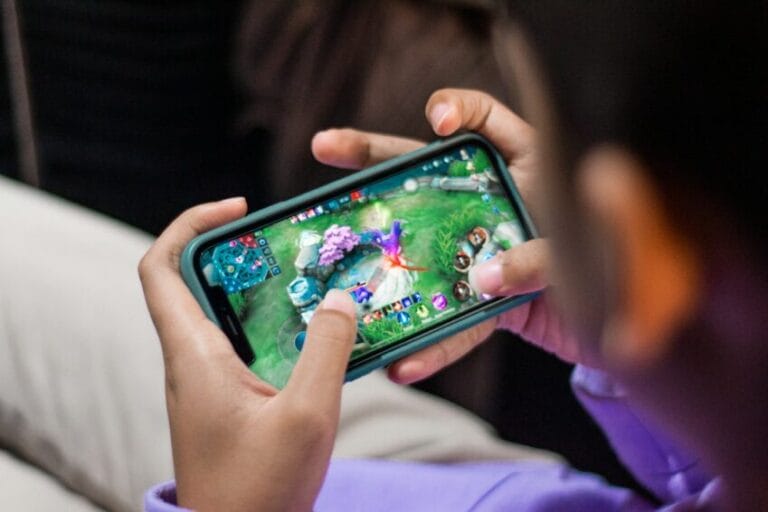 Hands holding a smartphone while playing a mobile game, illustrating the decision to top up in-game currency like Mobile Legends diamonds in the Philippines