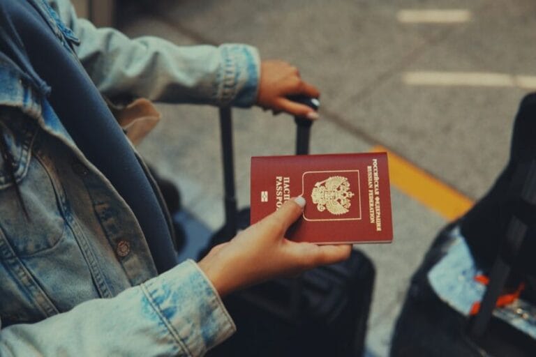 A red passport held in hand, representing the travel documents and proof of insurance cover required for Overseas Filipino Workers (OFWs) under the Migrant Workers Act and OWWA membership rules