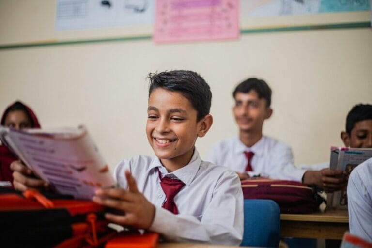 A student in school uniform in a classroom with a teacher, illustrating the private school vs. public school tuition decision in the Philippines
