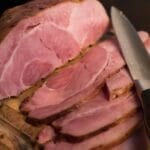 A whole Christmas ham sliced on a cutting board for a Noche Buena holiday table in the Philippines